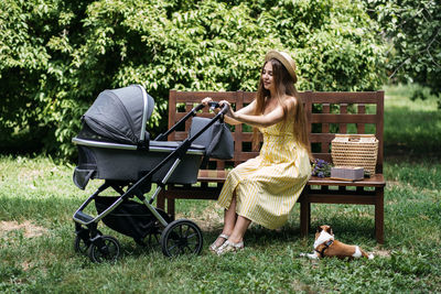 Baby strollers for newborn. young mother with newborn baby in stroller sitting on bench in the park