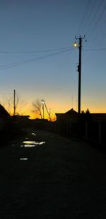 Silhouette city street against sky during sunset