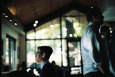 Side view of man and woman standing against window