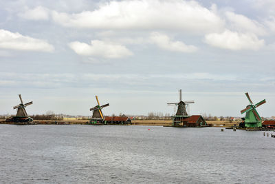 Traditional windmill by sea against sky