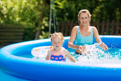 Cheerful healthy mother and daughter play in swimsuits in the pool. time together, summer time