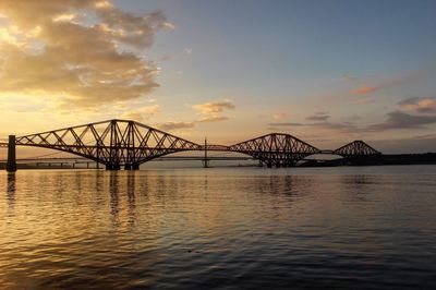 Forth bridge over sea against sky during sunset