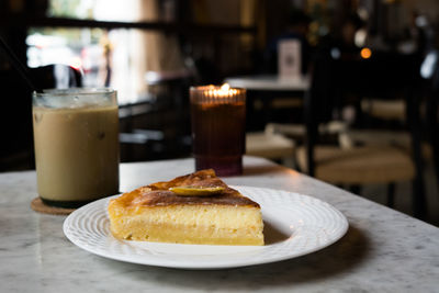 Sliced cheese lemon cake served with iced coffee on the table at the restaurant.