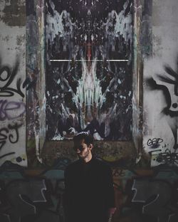 Young man standing against graffiti on wall