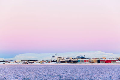 Buildings by sea against sky