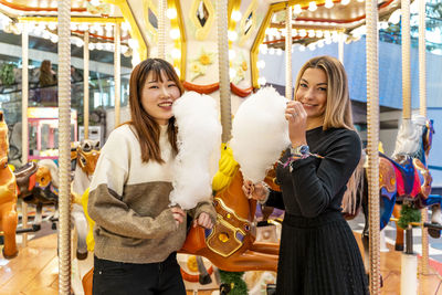 Couple of young multi-ethnic women eating cotton candy at a party. concept of millennial generation