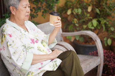 Portrait of young woman using mobile phone while sitting on bench