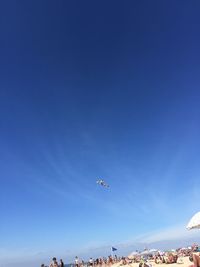 People at beach against clear blue sky