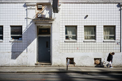 People walking on sidewalk by building in city