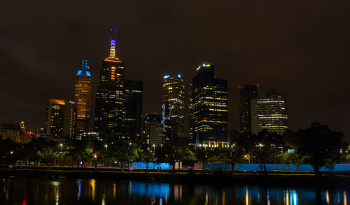 Illuminated buildings in city against sky at night