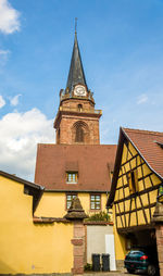 Low angle view of clock tower amidst buildings against sky