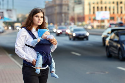 Portrait of young woman standing on street in city