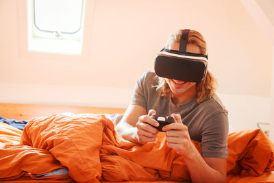 Man holding mobile phone while sitting on bed at home