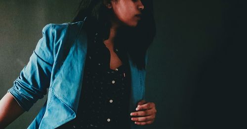Close-up of young woman standing against blue background