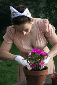 A woman replants an impatiens in a new pot