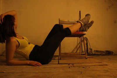 Side view of woman sitting on wooden floor