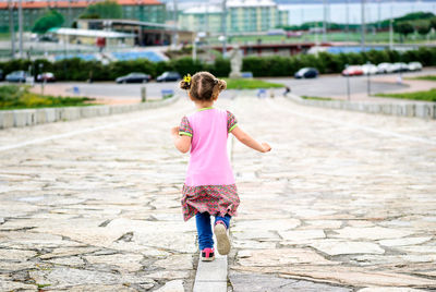 Rear view of girl running on footpath