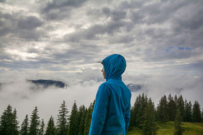 Man standing on mountain against cloudy sky