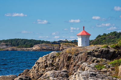 Lighthouse by sea against sky