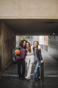 Smiling teenage girls standing together near underpass