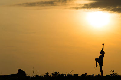 Silhouette pregnant woman exercising against sky during sunset