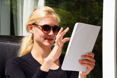 Smiling beautiful young woman using digital tablet outside house