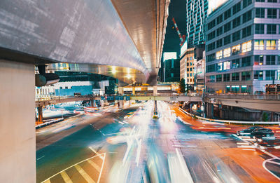 Light trails on road amidst buildings in city at night