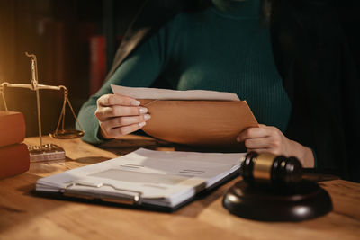 Midsection of woman reading book on table