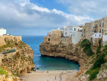 Buildings by sea against sky at polignano a mare