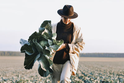 Woman picking cabbage vegetable at field. female farmer working at organic farm.harvesting at autumn