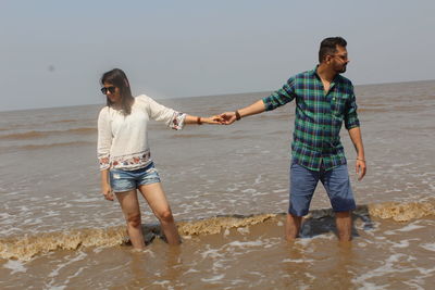 Full length of young couple standing on beach
