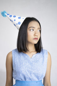 Beautiful young woman standing against white wall