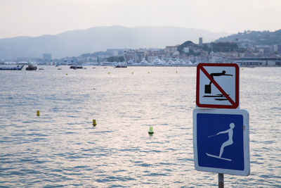 Warning sign by sea against sky