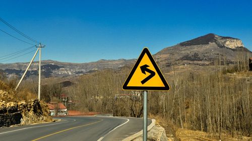 Road sign against clear blue sky