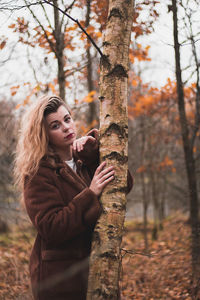Young woman looking at tree trunk in forest