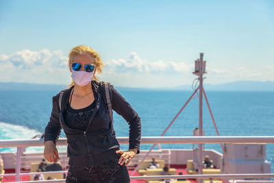 Man wearing sunglasses standing by sea against sky