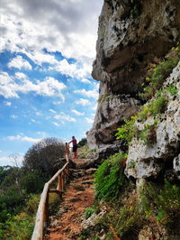 Rear view of woman on rock against sky