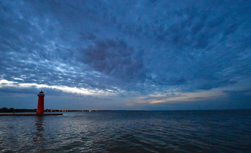 Lighthouse by sea against sky
