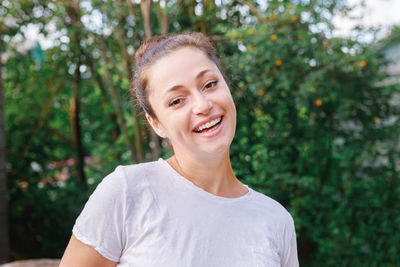 Portrait of young woman standing against trees