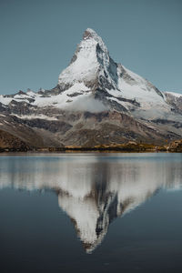 Scenic view of lake and snowcapped mountains against clear sky