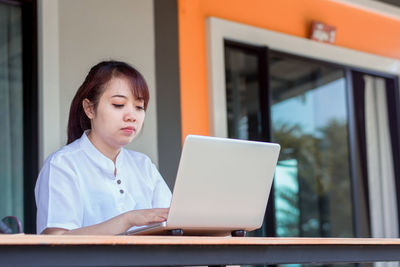 Young woman using phone while sitting on table