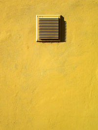 Full frame shot of yellow wall with air duct