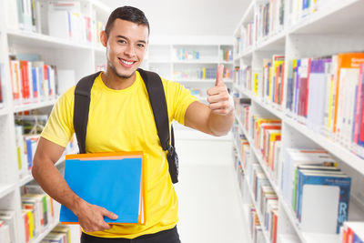 Portrait of young man standing in book