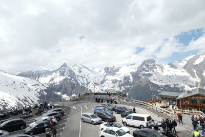 Cars on road by snowcapped mountains against sky