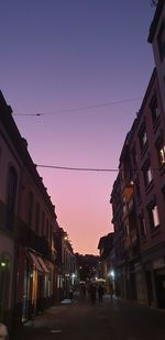 Street amidst buildings against sky at dusk