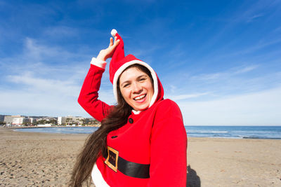 Portrait of smiling young woman at beach against sky