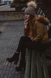 Full length of thoughtful woman sitting on bench