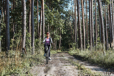 Active woman cycling on forest road. female riding bicycle off-road route on summer vacation day