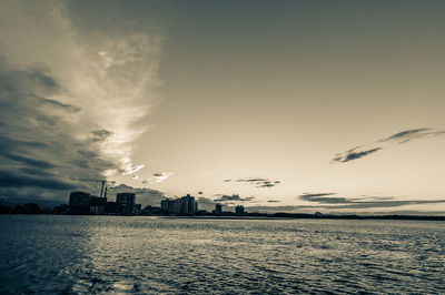 City by sea against sky at sunset