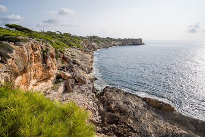 Scenic view of sea by cliff against sky